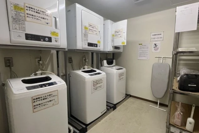 リゾートバイトの寮の共用ランドリー。洗濯機、乾燥機、アイロン台が完備されており、いつでも利用できます。