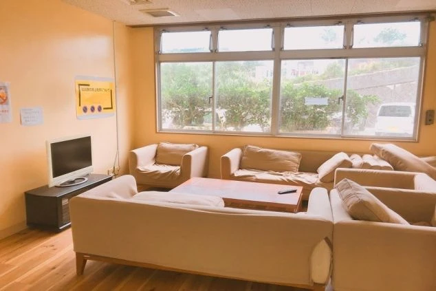 沖縄でリゾートバイトをするスタッフが住む寮の共用リビングの画像。ソファとテレビがある。