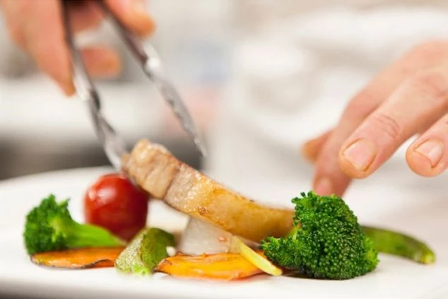 野菜や肉を使って芸術的に盛り付けをする料理人の写真。調理補助のリゾートバイトの業務イメージ。