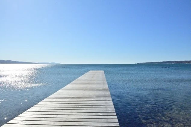 穏やかな海にまっすぐ伸びる、木製の桟橋の写真。リゾートバイトの仕事終わりや休日に、こんな開放的な景色を眺めながら、ゆっくりとリフレッシュできる魅力を伝えます。