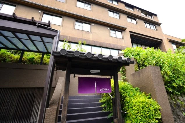 リゾートバイトの勤務先の外観を表現するイメージ画像。豊かな緑に囲まれた高台に立つ落ち着いた茶色の建物