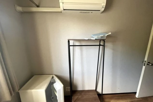 リゾートバイトの寮内の冷蔵庫とエアコン、ラックの画像。