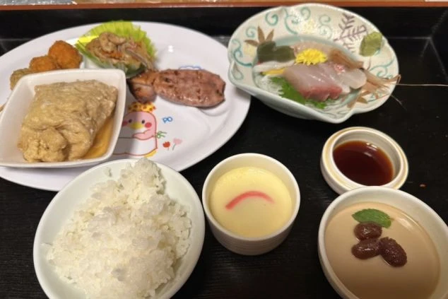 リゾートバイトの食事として提供されるまかない料理の画像。ご飯、茶碗蒸し、お刺身、煮物、デザートなど。