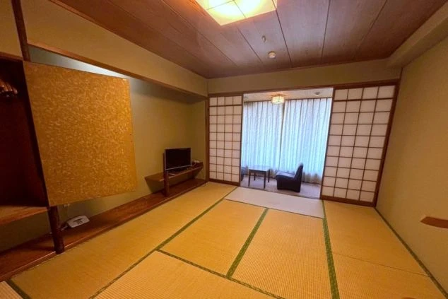 和室の寮の部屋の中を撮影した画像。部屋にはテレビとクローゼットが備え付けられており、隣の部屋は襖で仕切られている。リゾートバイトの寮の部屋の画像。