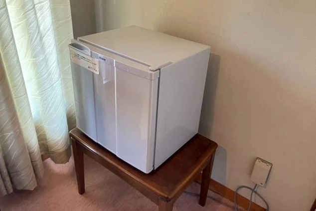 リゾートバイトの寮に備え付けられた冷蔵庫の画像。冷蔵庫は小型で、リゾートバイト中の食料や飲み物を入れておくのに便利である。寮の部屋にある冷蔵庫の画像。