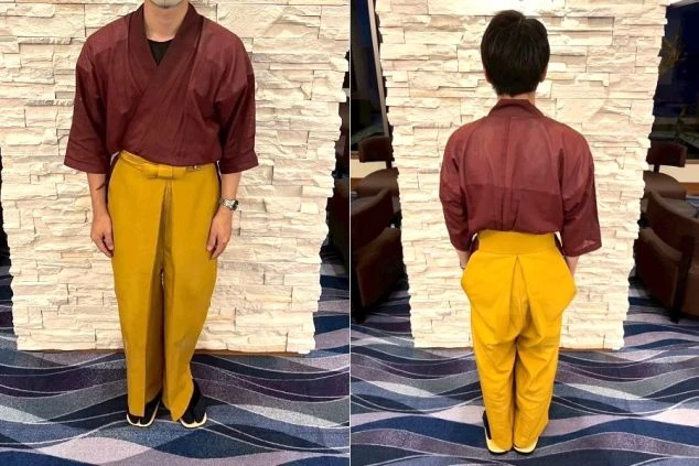 ワインレッドの作務衣に、からし色の袴風ズボンを着用。