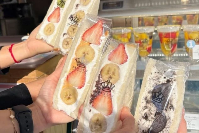 「熱海フルーツキング」のフルーツサンド。いちごとバナナが入ったフルーツサンドが3つと、オレオのサンドが1つ写っており、奥にはカラフルなゼリーが並んでいる。