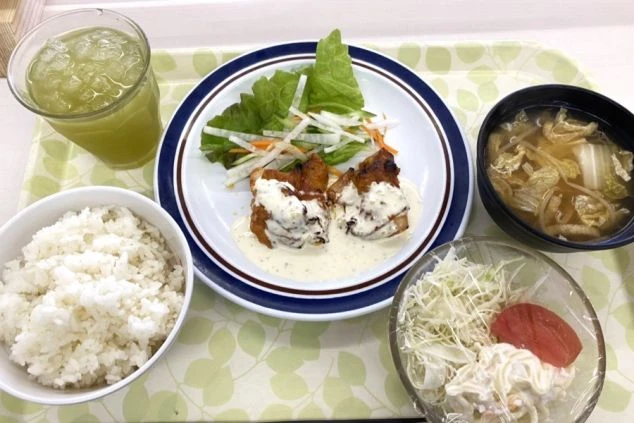 まかないを表現するイメージ画像。チキン南蛮とサラダ、ご飯と味噌汁、飲み物がセットになった定食。