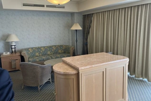 リゾートバイトの社員寮の部屋を表現するイメージ画像。花柄のソファとテーブル、椅子が置かれた広々とした洋室。