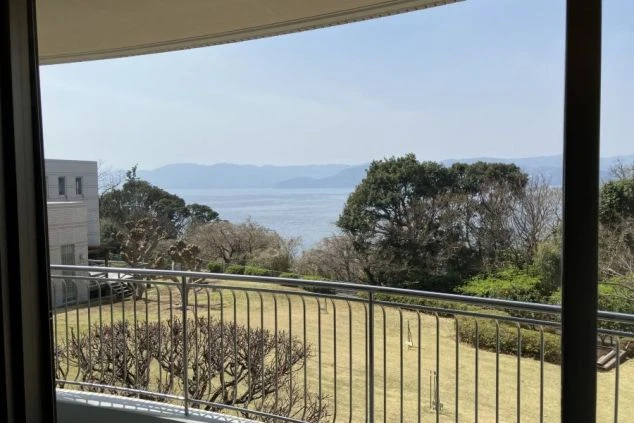リゾートバイトの社員寮の部屋を表現するイメージ画像。窓から海と庭園が一望できる広々とした部屋。