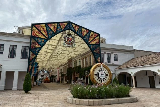 カラフルなステンドグラス風のアーチが通路を覆い、手前には方位磁石を模したゴールドのモニュメントが配置されています。