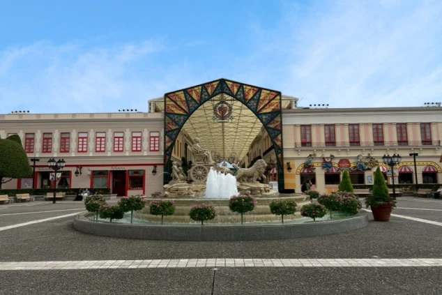 白壁と瓦屋根の建物に囲まれた中庭。中央にはコスモスが植えられた花壇と、スペインの雰囲気を感じさせる大きな方位磁石のオブジェがあります。