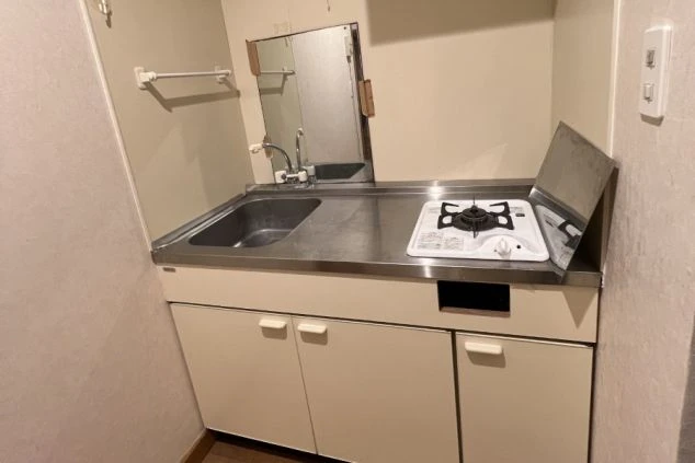 ワクトリの社員が出張で撮影した、リゾートバイトの寮に備え付けられたコンパクトなキッチン。シンク、ガスコンロ、収納棚が一体となっており、自炊も可能な生活環境を示している。