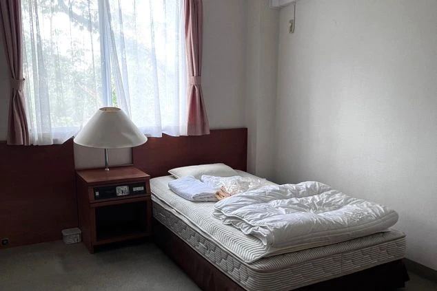 リゾートバイトの社員寮の部屋を表現するイメージ画像。窓から光が差し込む、ベッドとテーブルがあるシンプルな個室。