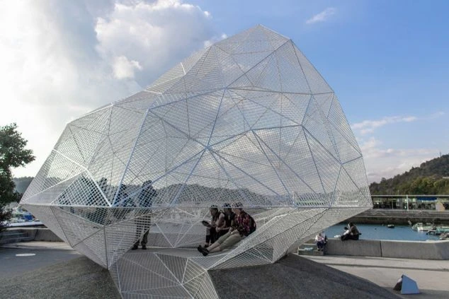 直島の宮浦港側にある、白いメッシュ構造が特徴的なアート作品「パビリオン」。人々が中に入ってくつろぐ様子が見られます。