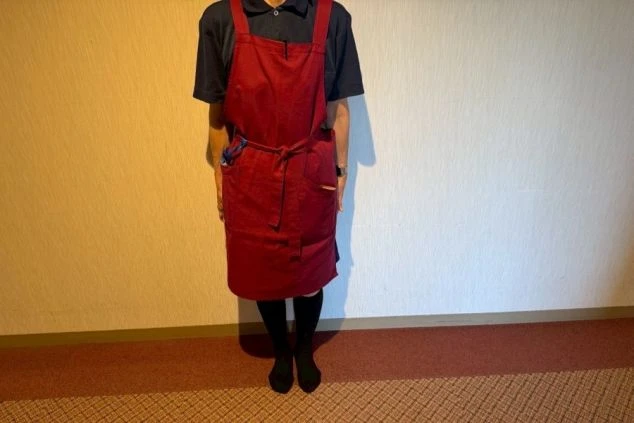 リゾートバイトの仕事風景を表現するイメージ画像。客室清掃の仕事で着用する、赤いエプロンと紺色のポロシャツ。