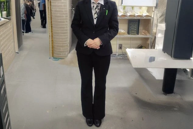 フロントで働く女性。黒いジャケットとパンツを着用した制服で、清潔感のある雰囲気を演出。