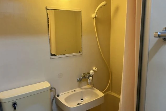 リゾートバイト寮のユニットバス。洗面台と浴槽、シャワーカーテンが備え付けられている。