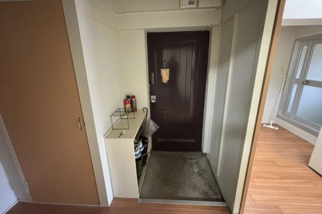 寮の玄関。ドアの横に下駄箱と収納棚が映る。