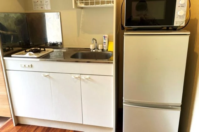 ワクトリの社員が出張で撮影した、リゾートバイトの寮のキッチンの画像。コンパクトなシンク、ガスコンロ、そして冷蔵庫と電子レンジが一体となった設備が整っている。