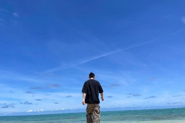  洞窟の窓から沖縄の美しい海を背景に、ハートマークを作る2人の女性