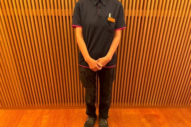 清掃スタッフの制服。黒のポロシャツとカーゴパンツ、サンダル姿。