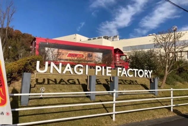 浜松にあるうなぎパイファクトリーの外観。大きな「UNAGI PIE FACTORY」の看板と、うなぎパイののぼり旗が見える工場見学施設の入り口。