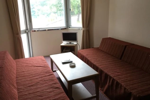 ワクトリの社員が出張で撮影した、寮の部屋の画像。窓際にテレビが置かれ、2つのソファが向かい合うように配置されたリビングスペース。リラックスして過ごせる、快適な寮生活の様子。