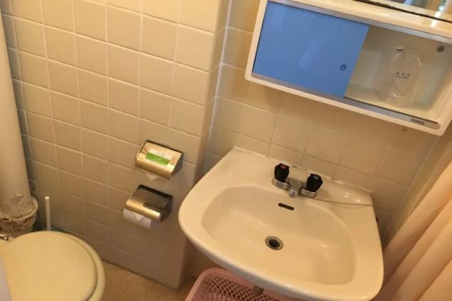 ワクトリの社員が出張で撮影した、タイル張りの壁に、洗面台とトイレが一体となったコンパクトな空間の画像。棚やトイレットペーパーホルダーも見える。リゾートバイト中の日常生活で利用する水回りの設備。