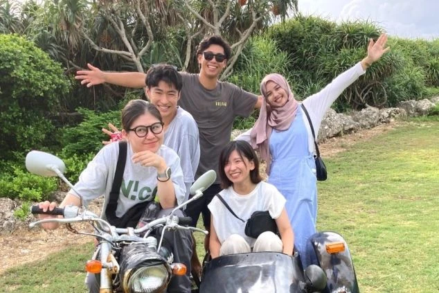 サイドカー付きバイクに乗り、楽しそうにポーズをとる若者たち。リゾートバイトの仲間との思い出作り。