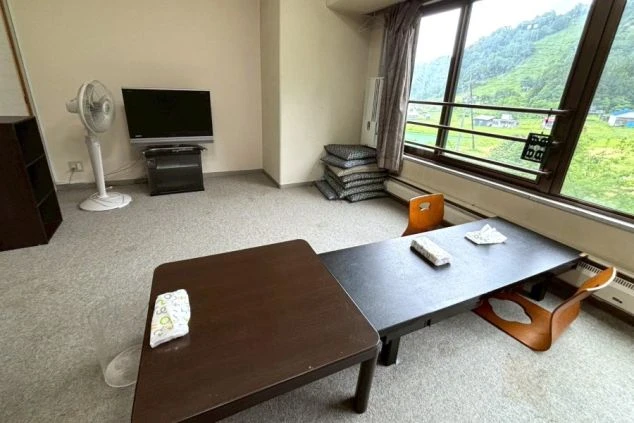 リゾートバイトの寮の共用スペース。テレビや座卓、座布団が用意されており、仲間と談笑したり、リラックスしたりできる場所をアピール。