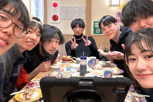 リゾートバイト中に仲良くなった同僚たちと、休日に回転寿司店で食事を楽しむ様子の画像。