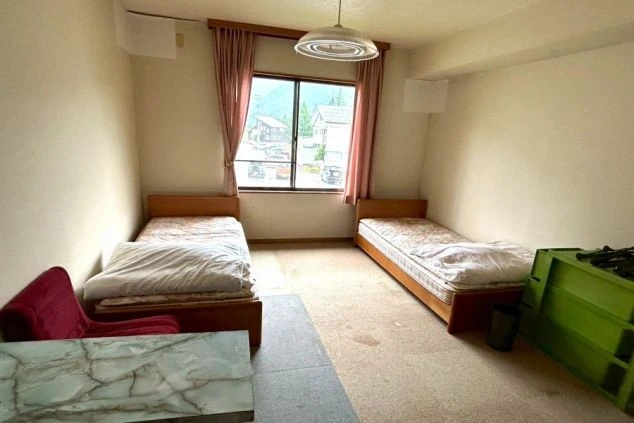 リゾートバイトの寮にある相部屋。2つのベッドが並び、窓からは外の景色が見える。