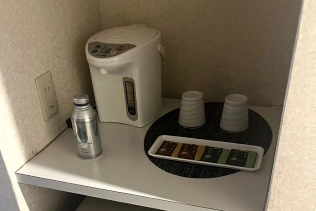 ワクトリの社員が出張で撮影した、リゾートバイトの客室寮の備品の画像。電気ポット、コップ2つ、ミネラルウォーターのボトル、そして様々なお茶のティーバッグがトレイに並んでいる。