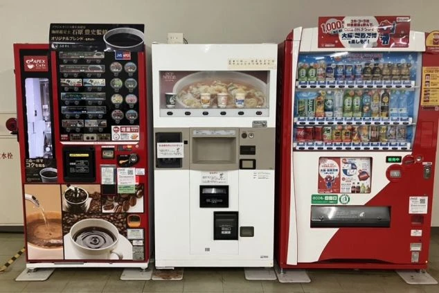 ワクトリの社員が出張で撮影した、リゾートバイトの寮の共用部に設置された3台の自動販売機の画像。左からコーヒー、カップ麺、飲料の自動販売機が並び、リゾートバイト中の食事や休憩に便利な設備。