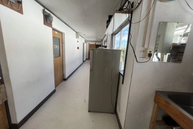 リゾートバイト男性寮の共同廊下の画像。各部屋へのドアが並び、共同で利用できる冷蔵庫と簡易シンクが設置されており、共同生活に便利。