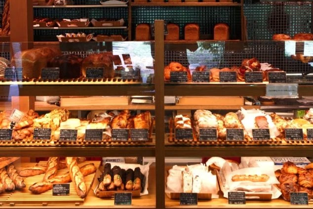 軽井沢のベーカリーのパン売り場の画像。ショーケースに様々な種類の焼きたてのパンが豊富に並べられ、食欲をそそる。リゾートバイトの勤務先となる店舗の、魅力的な商品陳列。