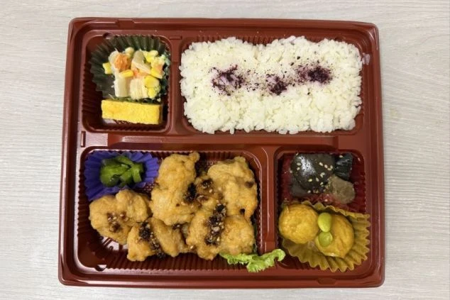 赤茶色のプラスチック容器に詰められた鶏天弁当。