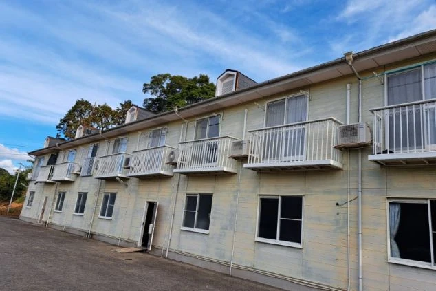 寮の外観。バルコニーとエアコン付きの建物。