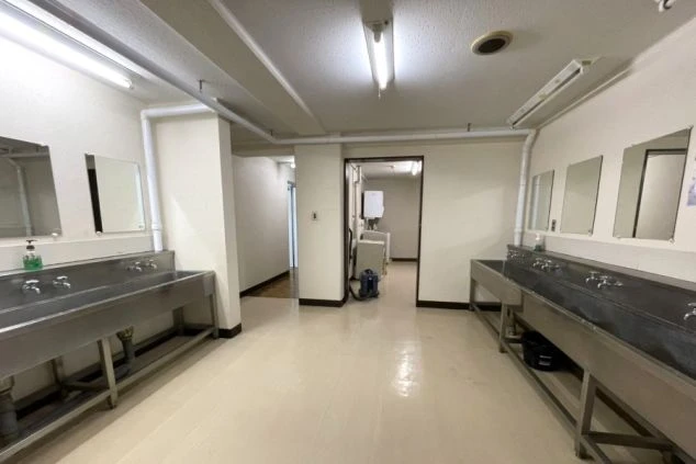 リゾートバイトの相部屋寮の共用洗面所の画像。奥には洗濯機がある