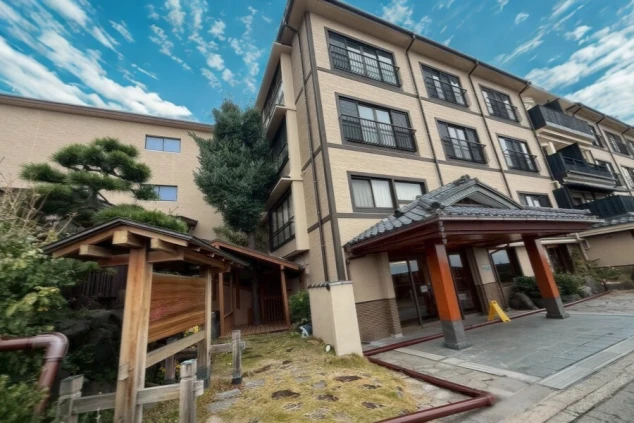 立派な瓦屋根の車寄せと、石畳の敷地、和の趣がある多階建ての建物が並んでいます。