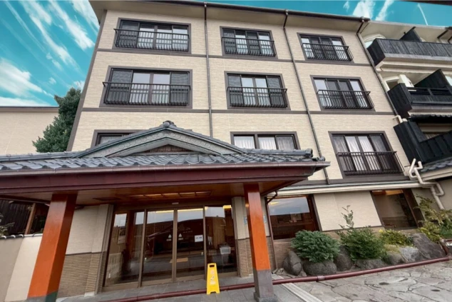 立派な瓦屋根の車寄せと、石畳の敷地、和の趣がある多階建ての建物が並んでいます。