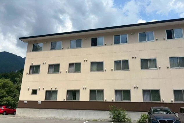 リゾートバイトの寮の外観の画像。3階建ての建物で、たくさんの窓がある。