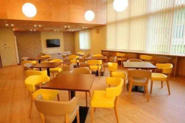 リゾートバイトの個室寮の談話スペースの画像。テーブルセットが複数あり、壁にはTVがある。