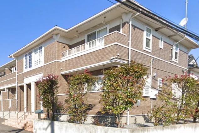 寮の外観。茶と白の外壁、バルコニー付きの建物。