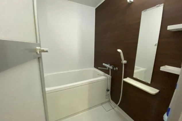 リゾートバイトの社員寮の部屋を表現するイメージ画像。茶色の木目調の壁の、浴槽とシャワーが備え付けられた独立風呂。