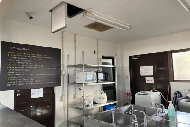 リゾートバイトの社員寮にある共用キッチンのイメージ画像。電子レンジやシンクが設置され、壁には利用マナーが書かれている。