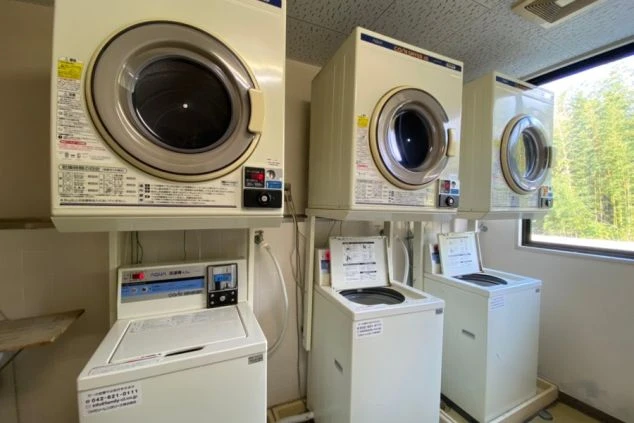 リゾートバイトの社員寮にある共用ランドリーのイメージ画像。洗濯機と乾燥機が複数台設置されている。