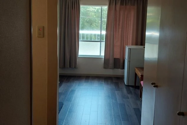 ワクトリの社員が出張で撮影した、リゾートバイトの寮の部屋の画像。濃い色のフローリングと窓際のカーテンが