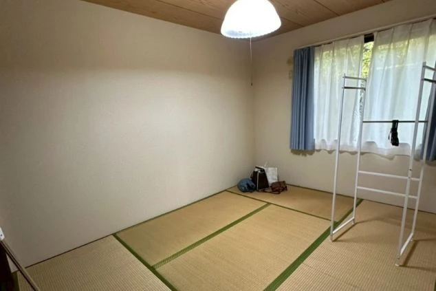 リゾートバイトの寮の部屋の画像。和室の畳の部屋に白い物干しラックが置かれている。リゾートバイトの寮の部屋の画像。